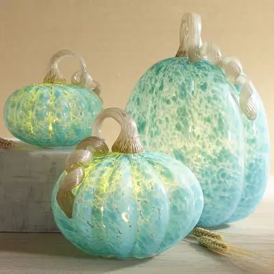 Three fresh blue glass pumpkins for fall decorating on a table.