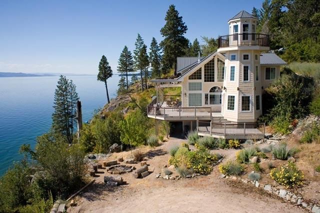 A lighthouse home sits atop a hill overlooking the water.