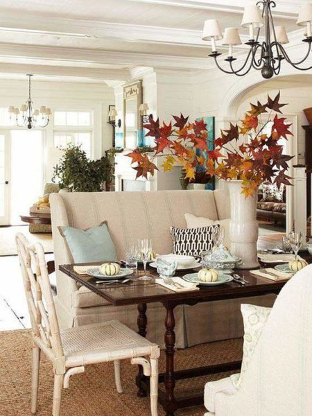 A dining room with fresh fall decorating featuring a white table and chairs.