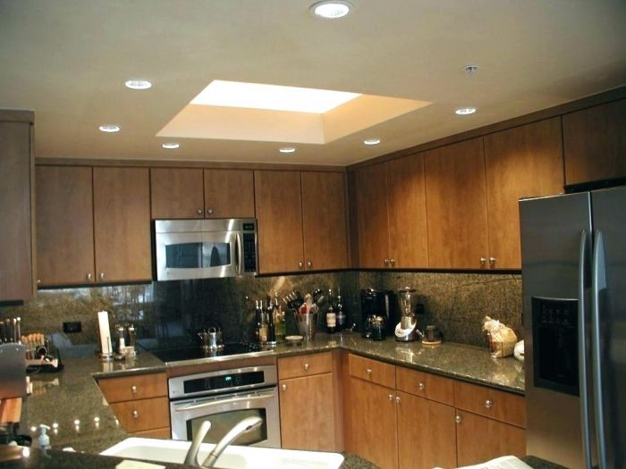 A kitchen with wooden cabinets and stainless steel appliances, with home lightning.