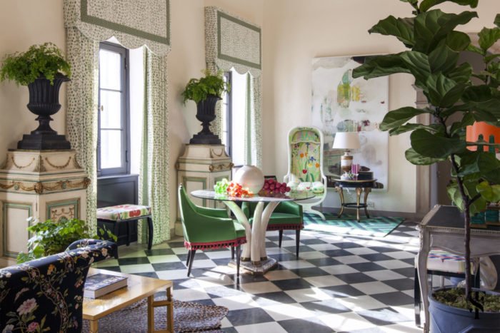 A living room with green plants and a checkered floor designed by Summer Thornton.
