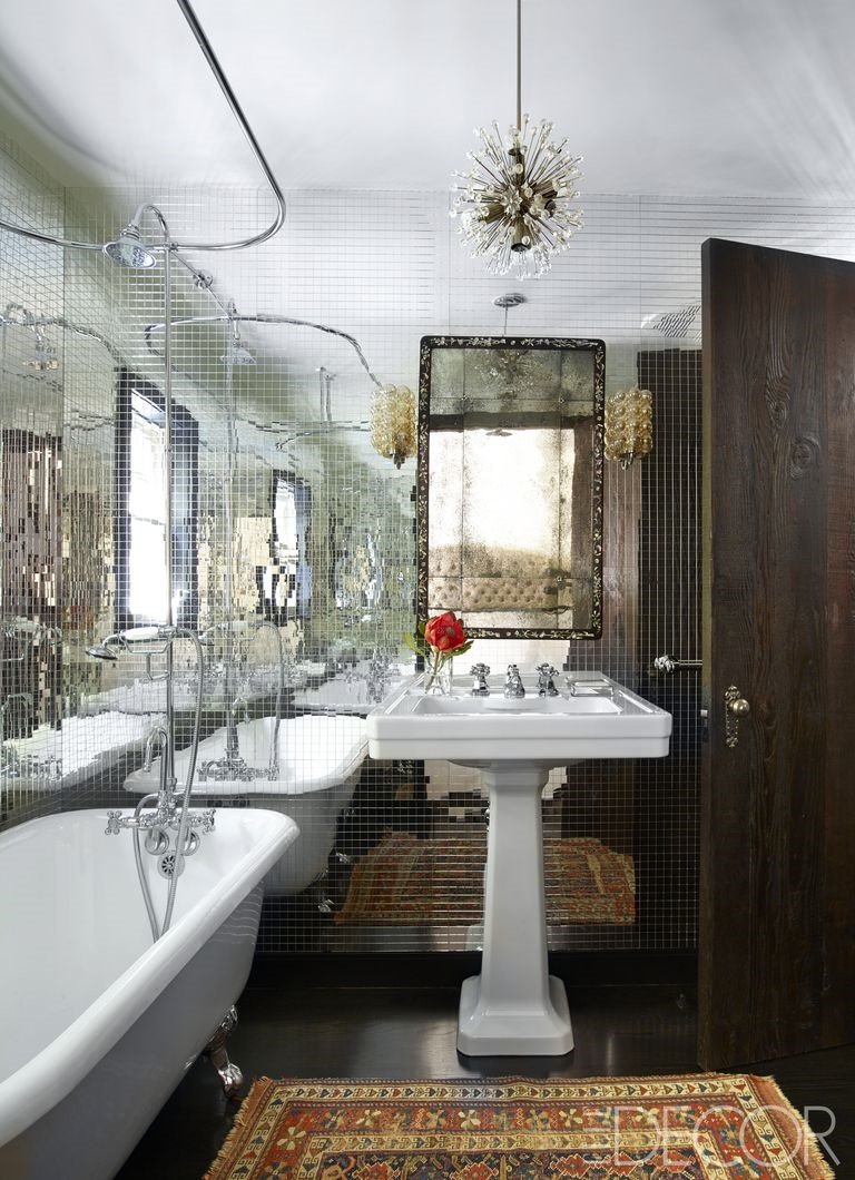 A small bathroom with mirrors and a rug.