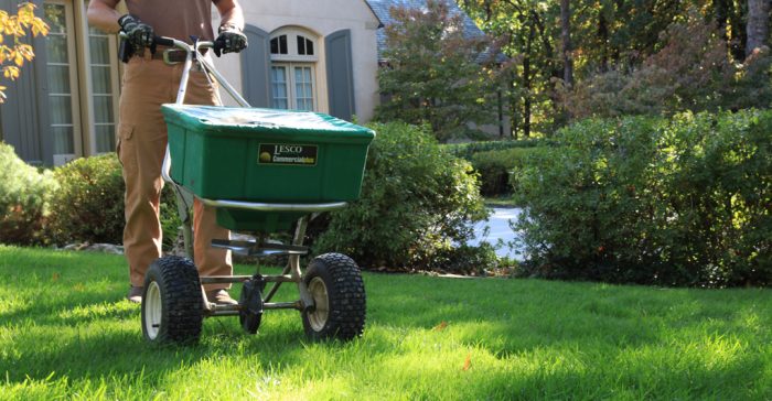 A man providing lawn maintenance services with a green cart.
