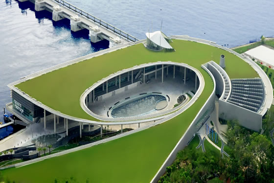 An aerial view of a building with a green roof next to a body of water, featuring one of the biggest plumbing projects.