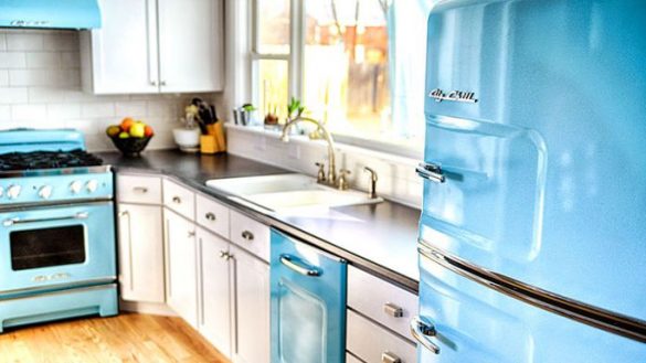 A vintage kitchen with a blue refrigerator and white cabinets.