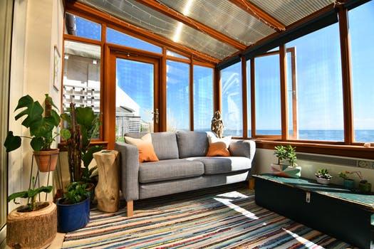 A sun room with a couch and a view of the ocean featuring the best windows.