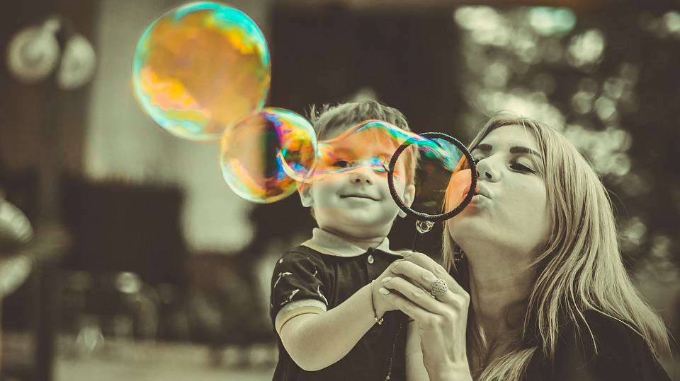 A mother creating household memories with her son by blowing soap bubbles.
