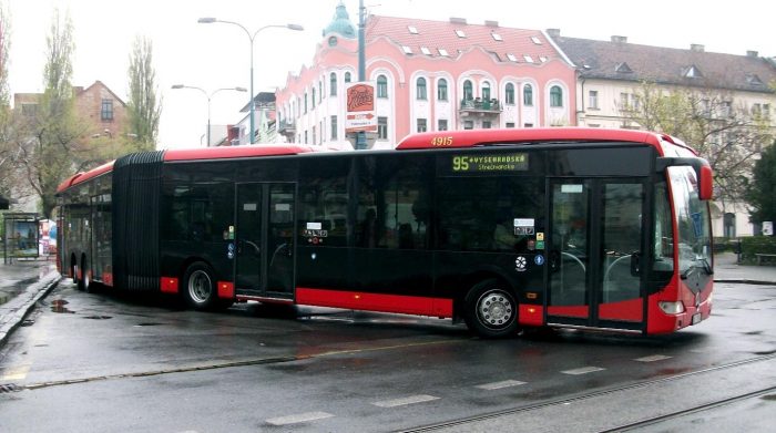 A bus parked on a wet street in Vienna ready to transport passengers to Budapest.