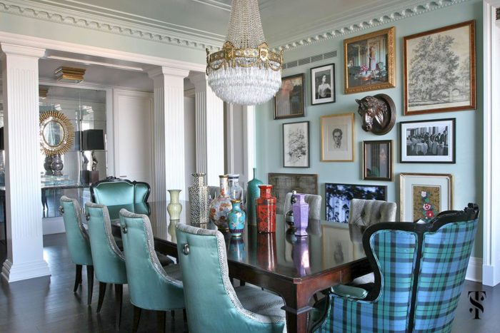 A dining room with blue chairs and pictures on the wall designed by Summer Thornton.