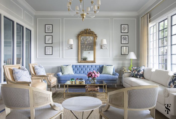 A living room designed by Summer Thornton with blue couches and a chandelier.
