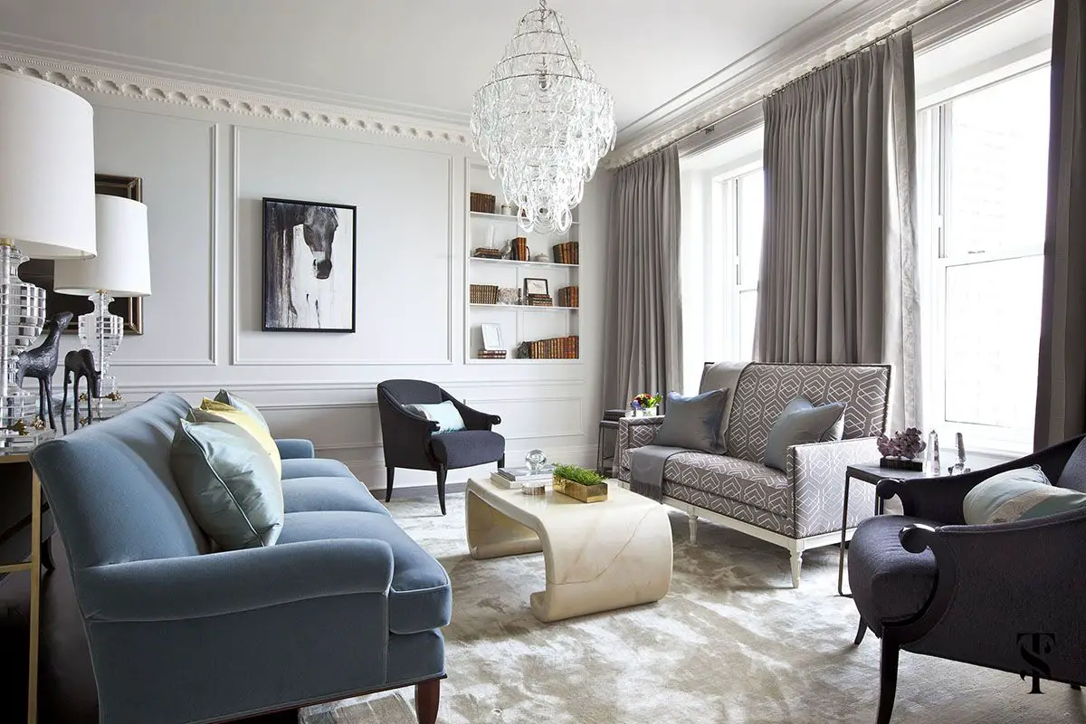 A living room with blue furniture and a chandelier designed by Summer Thornton.