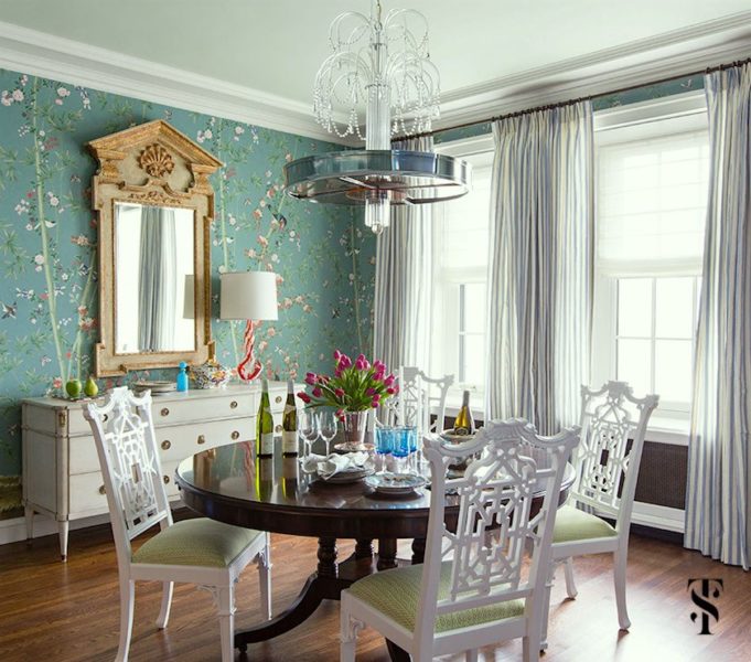 A dining room with blue wallpaper and white chairs designed by Summer Thornton.