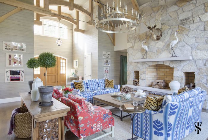 A living room designed by Summer Thornton with a stone fireplace and blue couches.