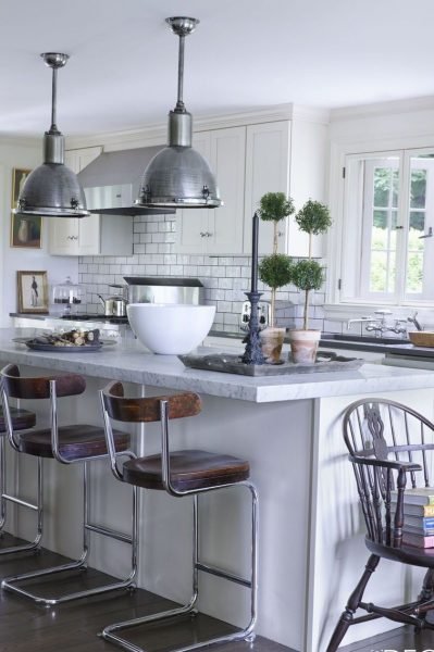A small white kitchen with a large island and stools.