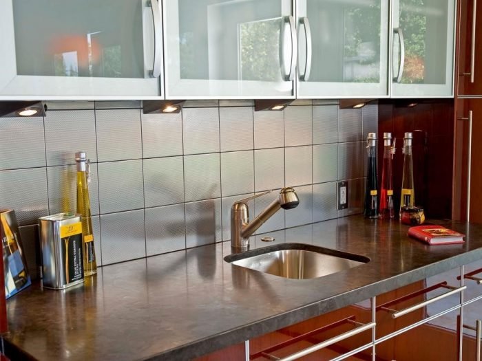 A small kitchen with a stainless steel sink and glass cabinets.
