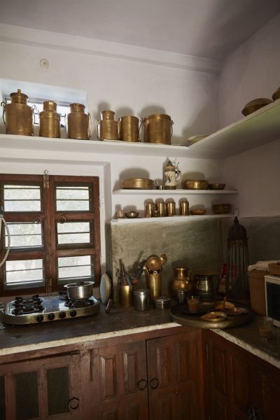 A small kitchen adorned with a plethora of brass pots and pans.