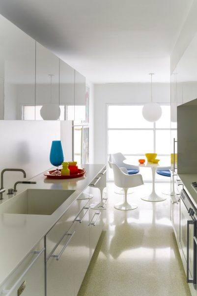 A modern kitchen with small white cabinets and white counter tops.