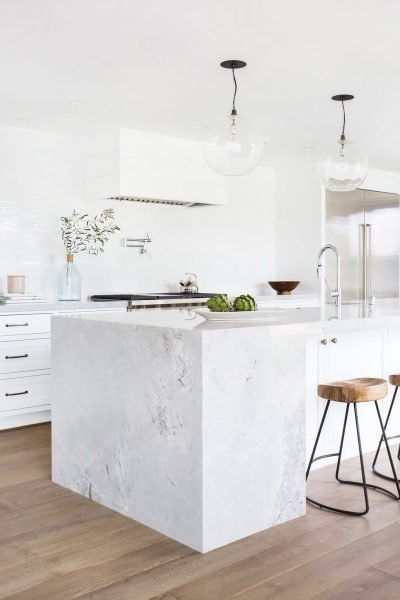 Small kitchen with a marble island and stools.