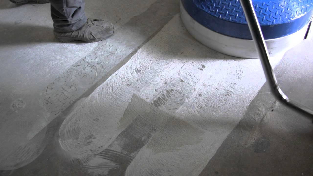 A person using a blue machine to clean concrete floors.