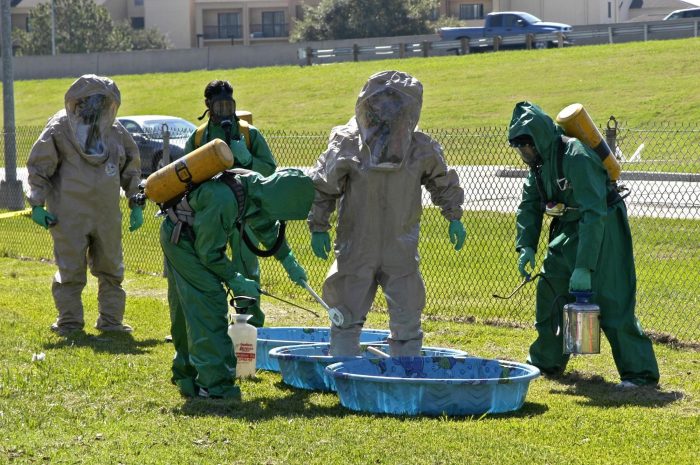 A group of people in hazardous protective gear standing in a field.
