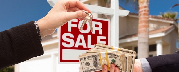 A man giving money to a woman in front of a for sale sign, indicating readiness to sell a house.