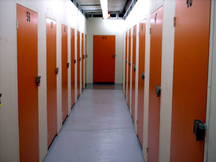 A row of orange doors in a warehouse storage room.