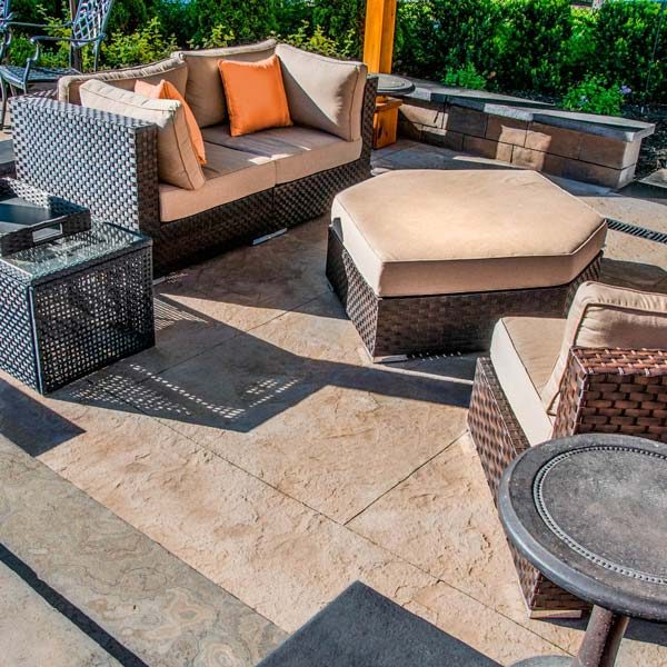 A patio with wicker furniture, a fire pit, and a stamped concrete driveway.
