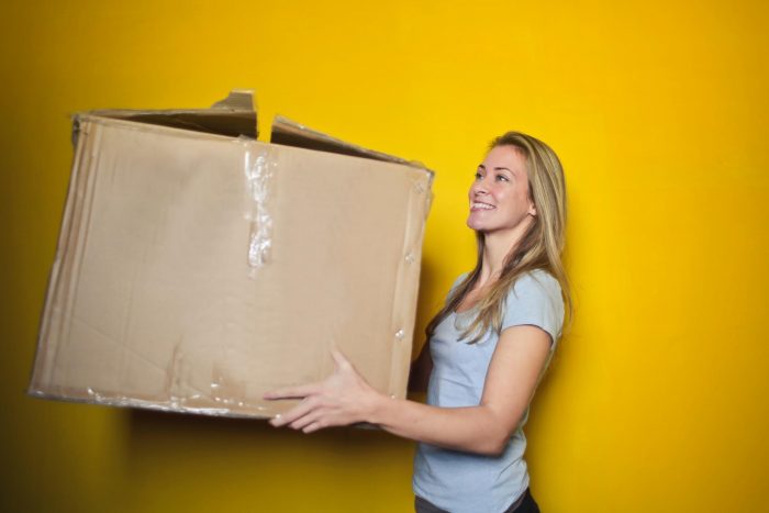 A woman holding a moving box while moving across.