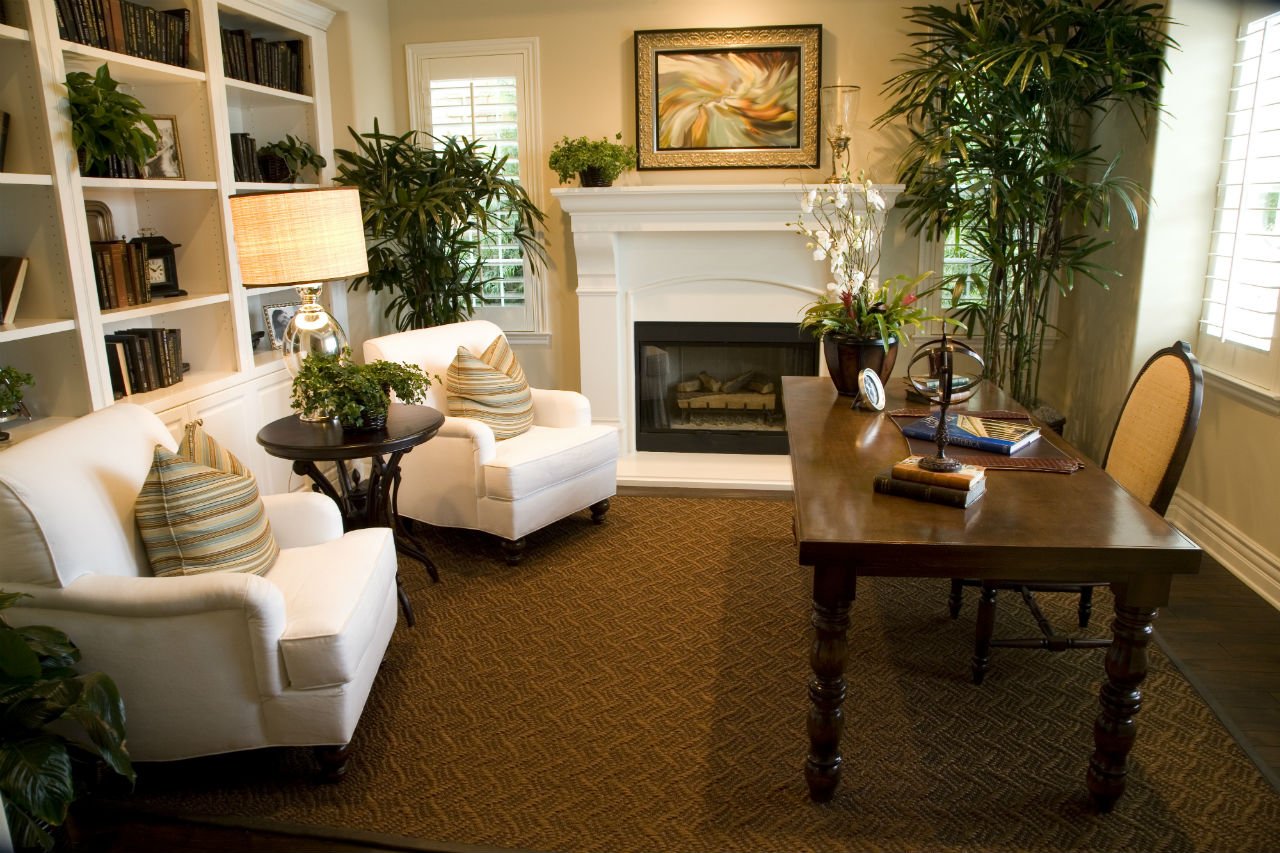 A home office with white furniture and a fireplace.