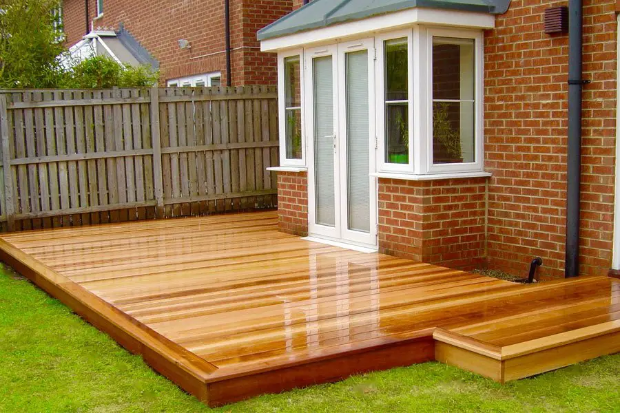 New wooden deck attached to red brick house.
