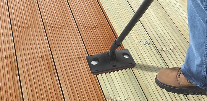 A person using a broom to clean a composite decking.
