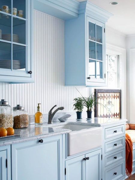 A kitchen with trendy blue cabinets and contemporary white counter tops.
