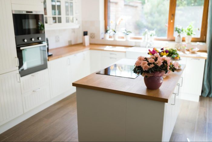A kitchen with flowers on the counter top and wall panels.
