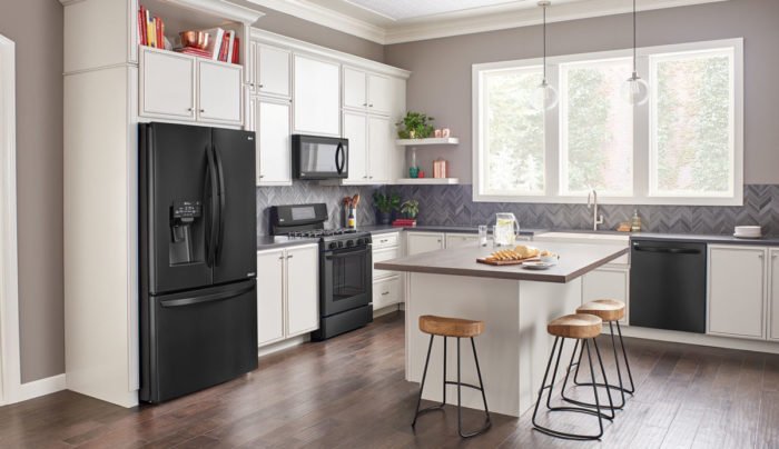A kitchen with black appliances and wood floors is one of the top kitchen trends of 2019.