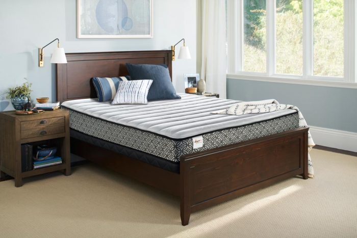 A comfortable mattress in a bedroom with a wooden bed frame.