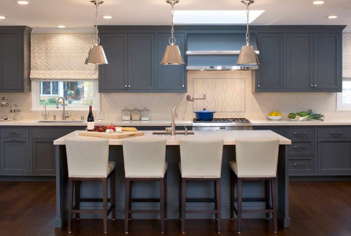 A kitchen with blue cabinetry and white counter tops.