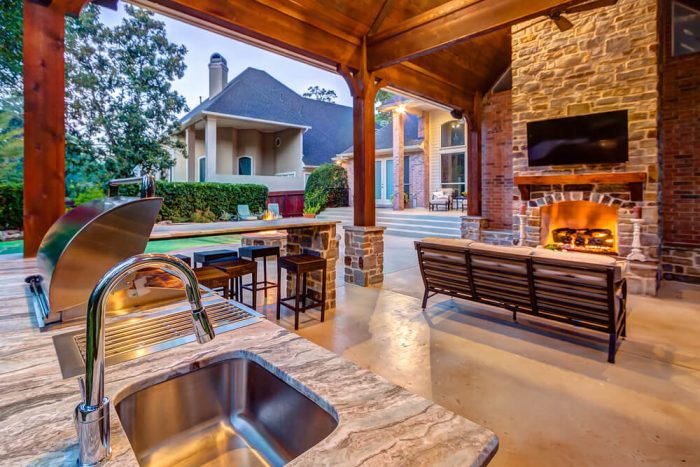 An outdoor kitchen with a fireplace and tv, featuring outdoor features.