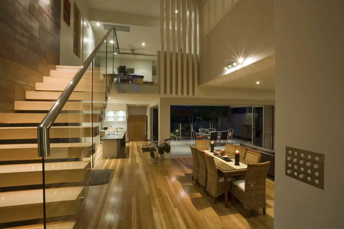 Modern home interior with wooden staircase and open dining area.