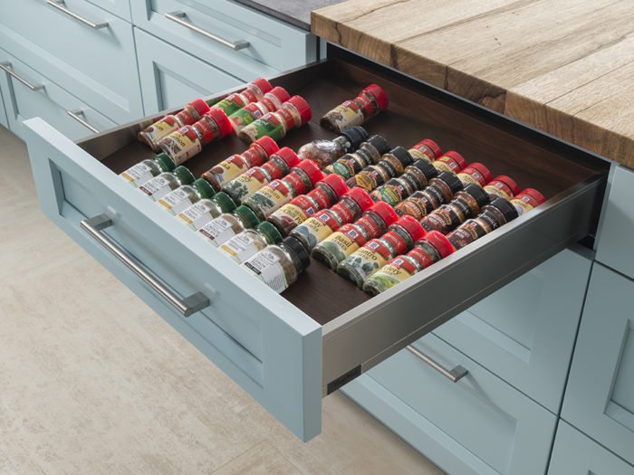 A spice drawer is open in a trendy kitchen.
