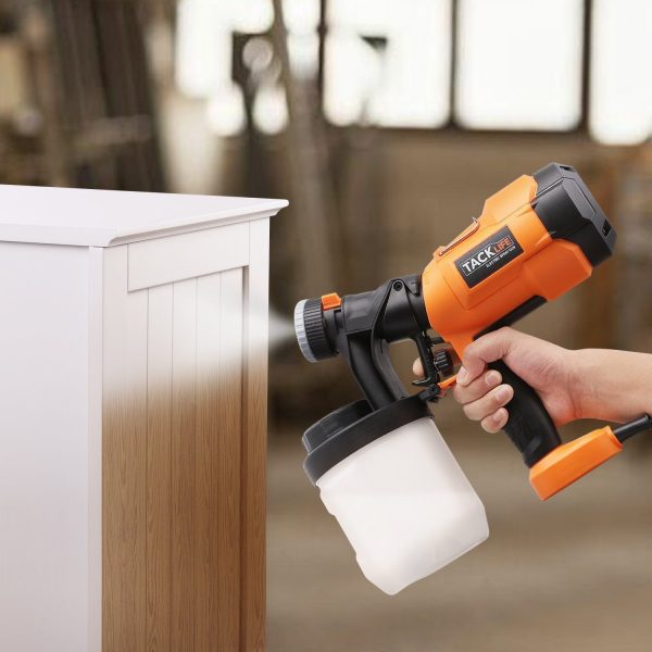 A person using a paint sprayer to guide their painting on a wooden cabinet.