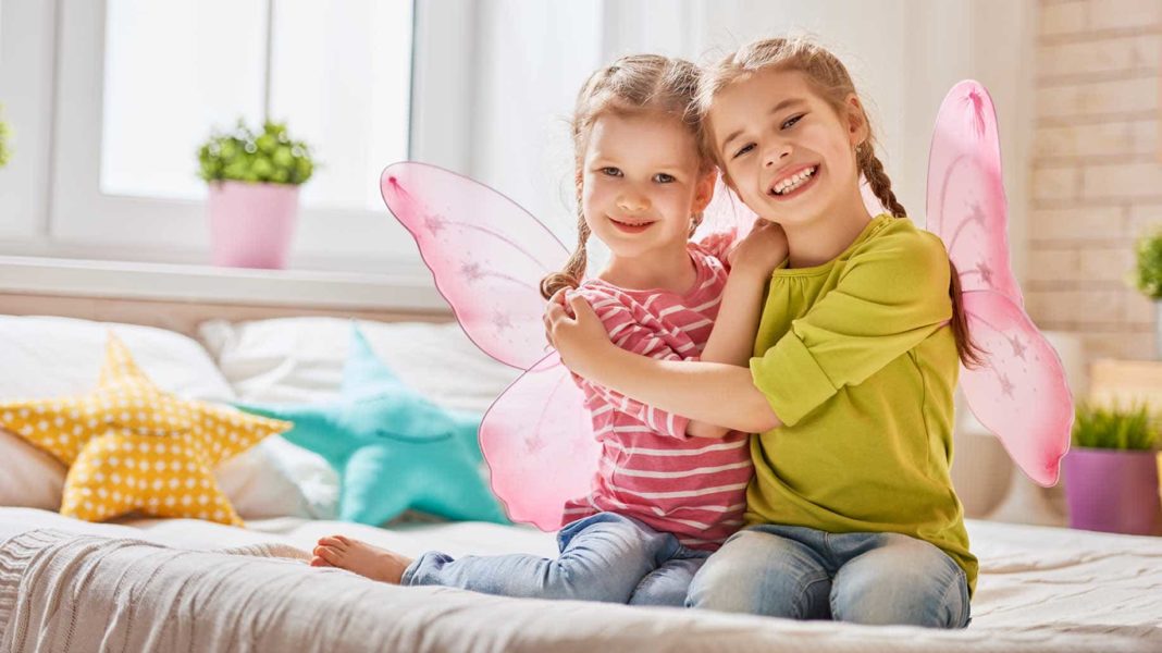 Two little girls sitting on a bed with natural tips for lower stress.