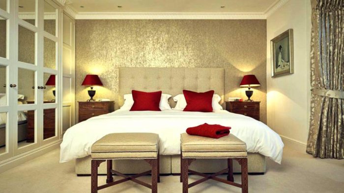 A bedroom with a white bed and red pillows.