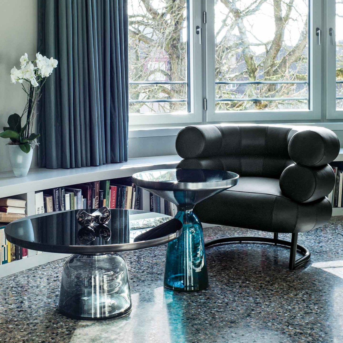 A living room with a black Eileen Gray Bibendum chair and a glass table.