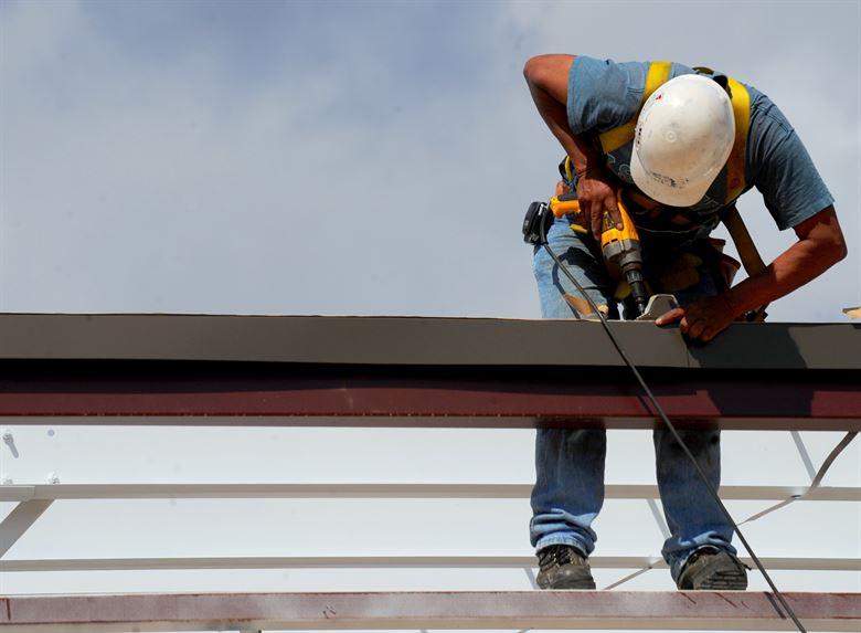 A construction worker specializing in home improvement working on a roof.