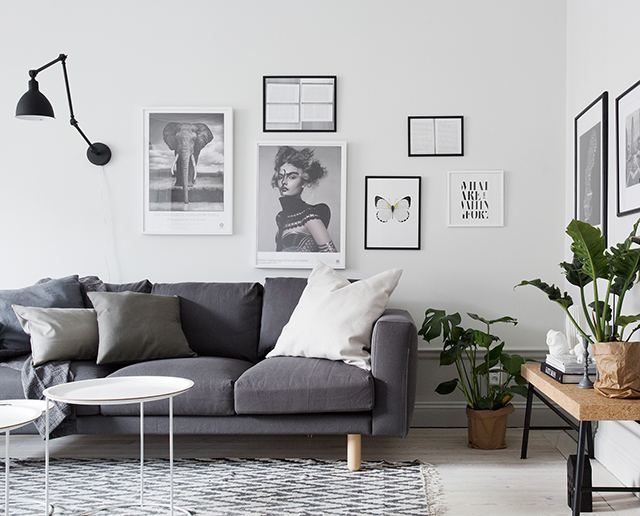 A studio apartment with a grey couch and framed pictures in the living room.