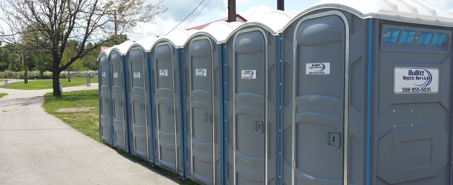 A row of portable toilets on a sidewalk.