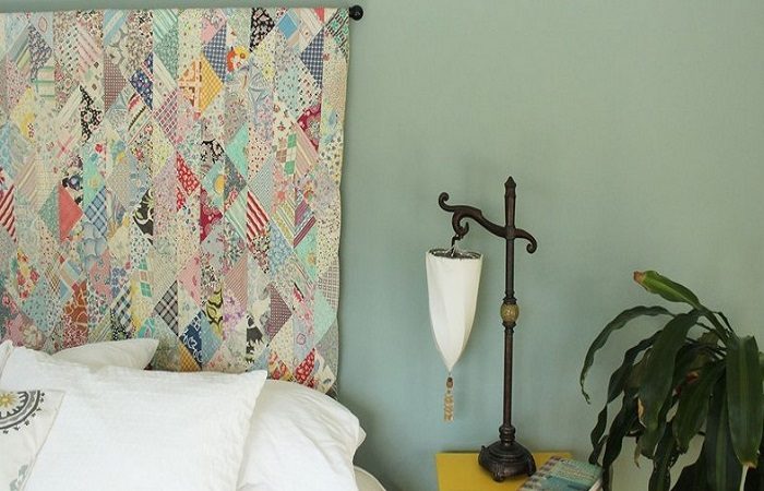 A bedroom with a colorful quilted headboard.