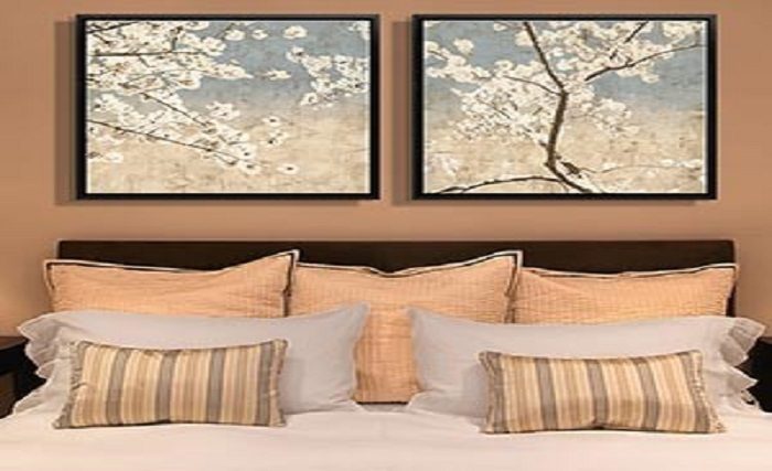 Two personalized framed pictures of cherry blossoms on a cozy bed.