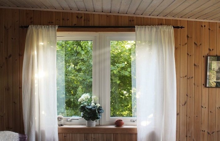 A window with wood paneling and drapes.