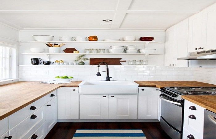 Interior kitchen with white cabinets and wooden counter tops.